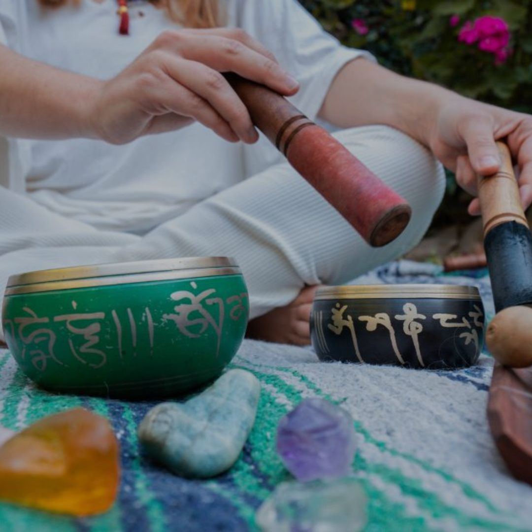 Person playing on singing bowls with crystals and stones on a colorful mat